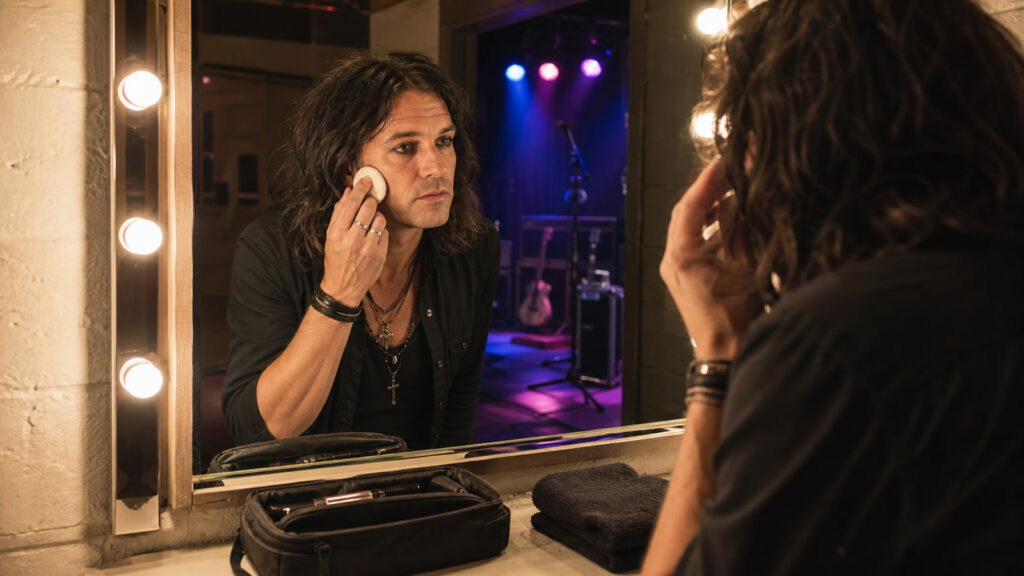 Músico prepara la piel y el maquillaje frente al espejo antes de salir al escenario
